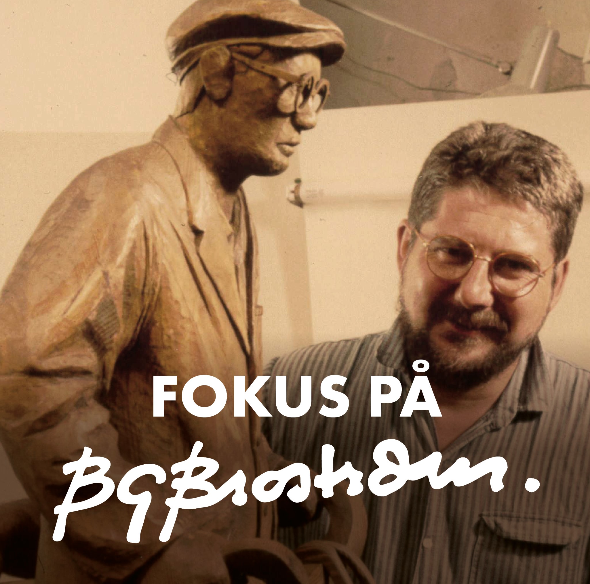 Foto: Lennart Olsson Syntolkad bildtext: En glad BG Broström står i sin ateljé bakom en stor träskulptur föreställande en man med kavaj, gubbkeps och glasögon.